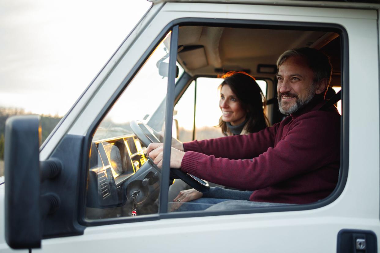 A mid-age couple is traveling with the RV. The husband is driving, and the wife sits next to him.