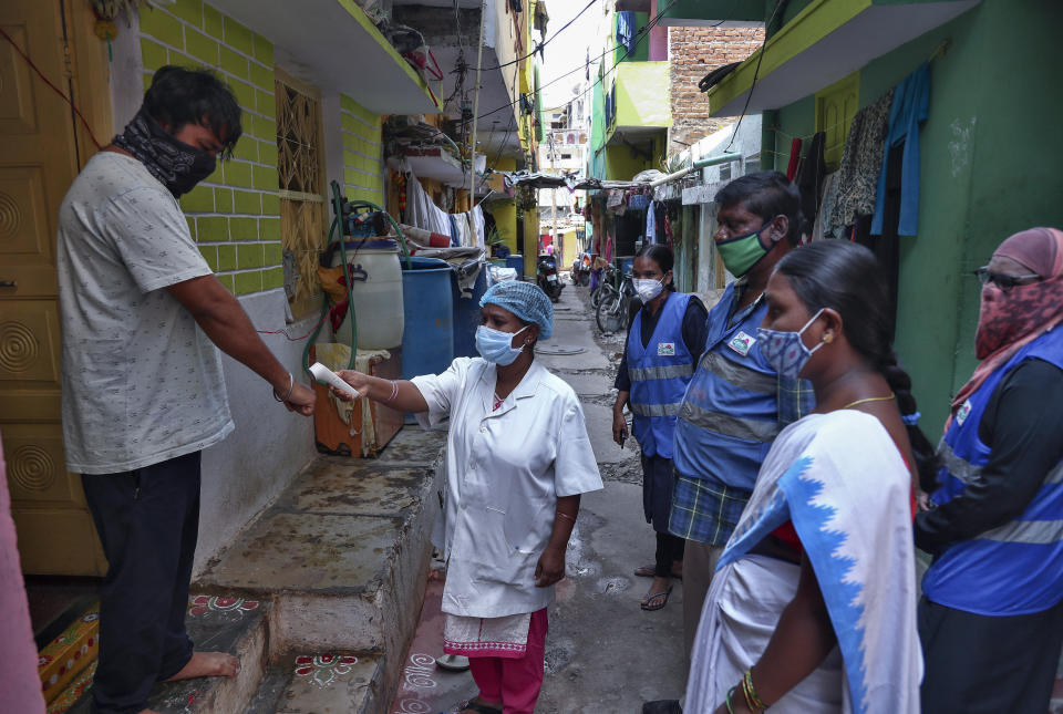 FILE - In this May 6, 2021, file photo, an Indian health worker checks body temperature of a man during a door-to-door survey being conducted as a precaution against COVID-19 in Hyderabad, India. The World Health Organization said Monday, May 10, that a worrisome variant was first detected in India may spread more easily. Scientists are still trying to figure out if it resulted in the terrifying surge of infections in the nation, and looking to see if this could this happen elsewhere. (AP Photo/Mahesh Kumar A., File)