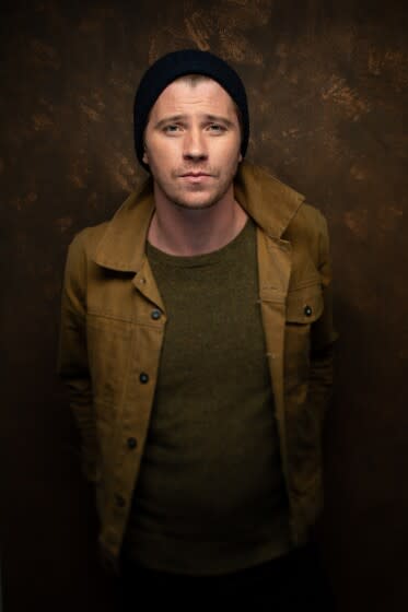 Garrett Hedlund posing in a black beanie and brown jacket