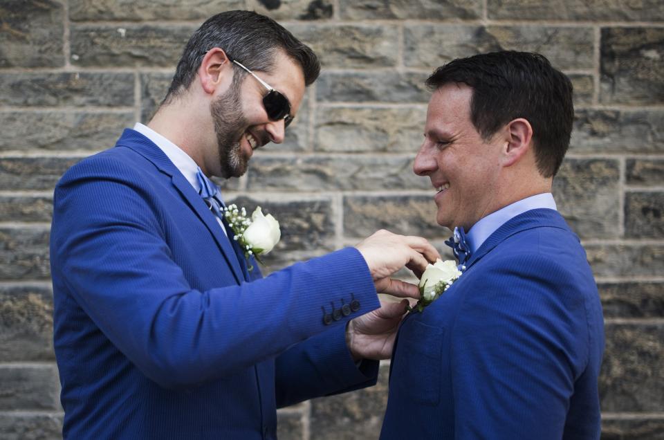 A couple adjusts each other's boutonniere before "The Celebration of Love", a grand wedding where over 100 LGBT couples got married, at Casa Loma in Toronto