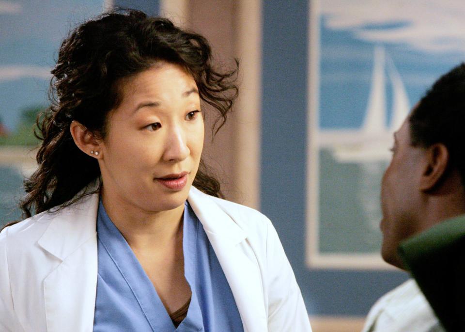 Two characters from Grey's Anatomy, one wearing a lab coat, engage in conversation
