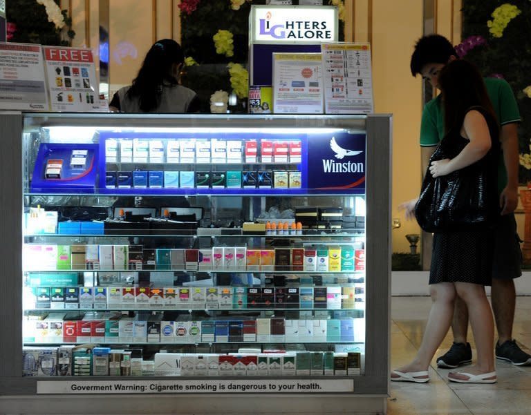 Customers looks at a stall selling cigarettes at a mall in Manila on April 12, 2013. The tobacco feeds the habit of more than 17 million Filipino smokers, or roughly 20 percent of the population, yielding nearly $700 million in annual tax revenues