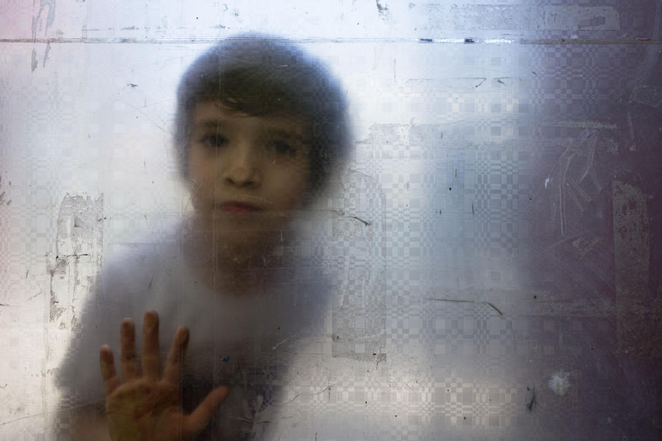 In this Dec.13, 2018 photo, Laura, a transgender girl, looks from behind a glass door during recess at the Amaranta Gomez school in Santiago, Chile. The school was launched in 2017 as a way to help families of trans children, who often skip classes or even fail to finish their studies as result of discrimination, said Selenna Foundation President Evelyn Silva. (AP Photo/Esteban Felix)