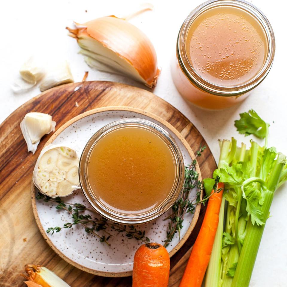 photo of beef bone broth in clear bowl with carrots and celery