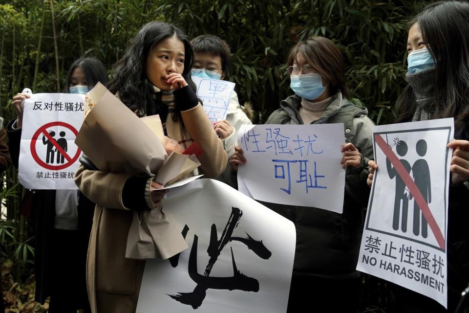 Zhou Xiaoxuan, foreground, walks by supporters holding banners as she arrives at a Beijing courthouse.