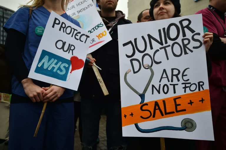 Junior doctors hold up placards on a picket line during a 24-hour strike over pay and conditions outside St Thomas' Hospital in London on February 10, 2016