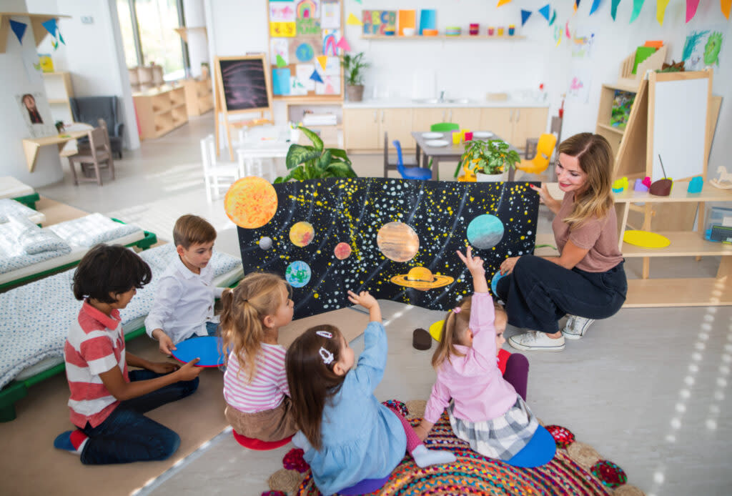A preschool teacher shows a poster of the planets to children. (Getty Images)
