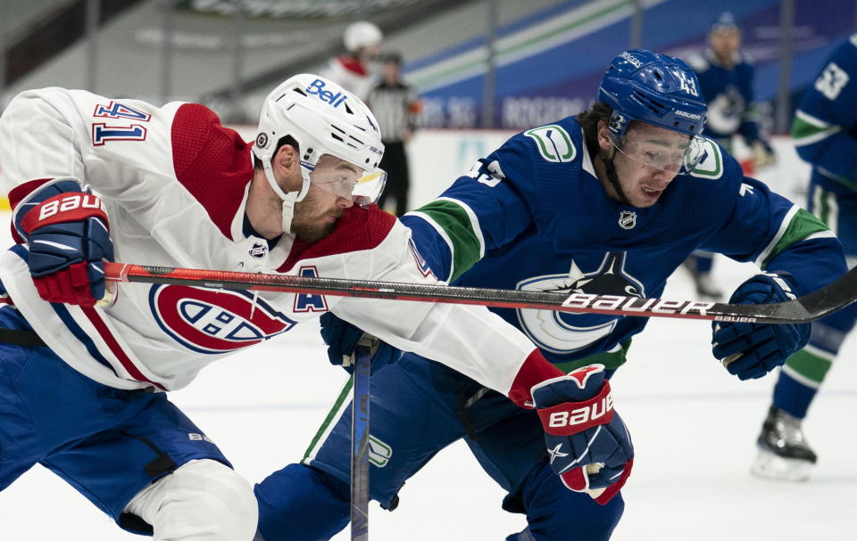 Montreal Canadiens right wing Paul Byron (41) fights for control of the puck with Vancouver Canucks defenseman Quinn Hughes (43) during first-period NHL hockey game action in Vancouver, British Columbia, Monday, March 8, 2021. (Jonathan Hayward/The Canadian Press via AP)