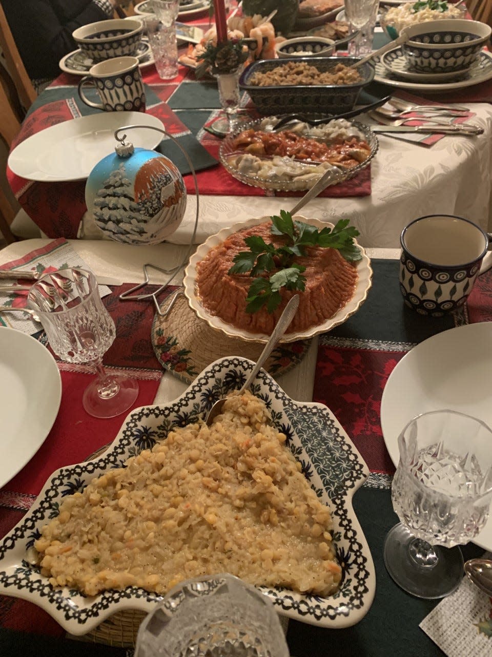 The Wigilia dinner table holds 12 dishes to represent the 12 apostles on Christmas Eve. Set with Boleslawiec Pottery dishes from Poland, the Burzynski family table includes sauerkraut and chickpeas, front, along with baked cod in tomato sauce and three preparations of herring.