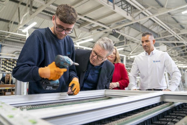 Sir Keir Starmer looks closely as an employee works on a window in a factory during a visit to Window Supply Company in Bathgate, West Lothian