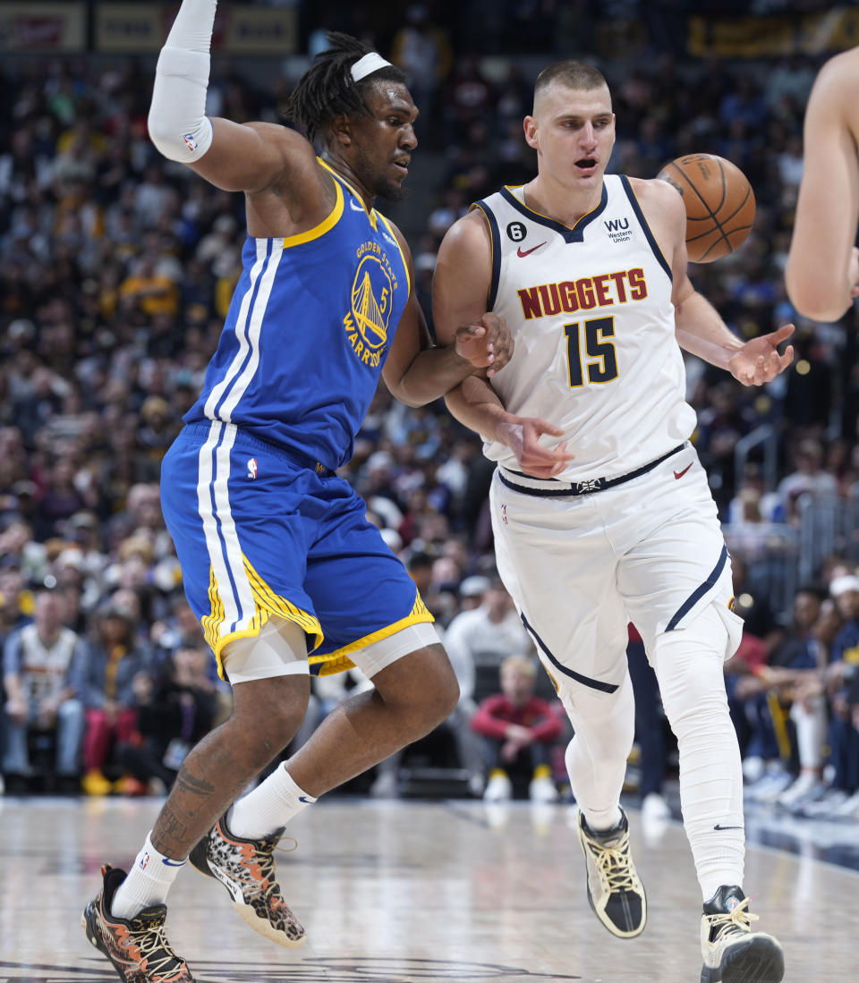 Denver Nuggets center Nikola Jokic, right, loses control of the ball while driving past Golden State Warriors forward Kevon Looney in the first half of an NBA basketball game, Thursday, Feb. 2, 2023, in Denver. (AP Photo/David Zalubowski)
