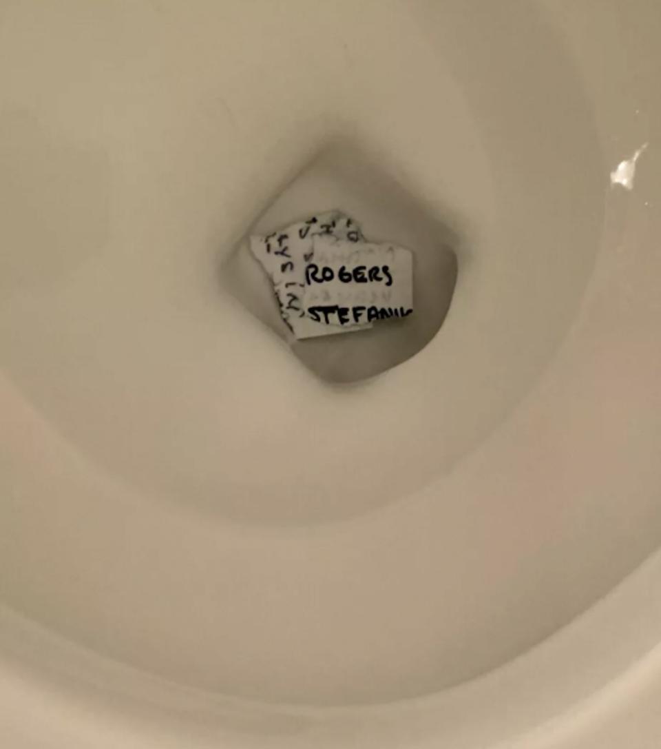 Pieces of paper with writing on them at the bottom of a toilet