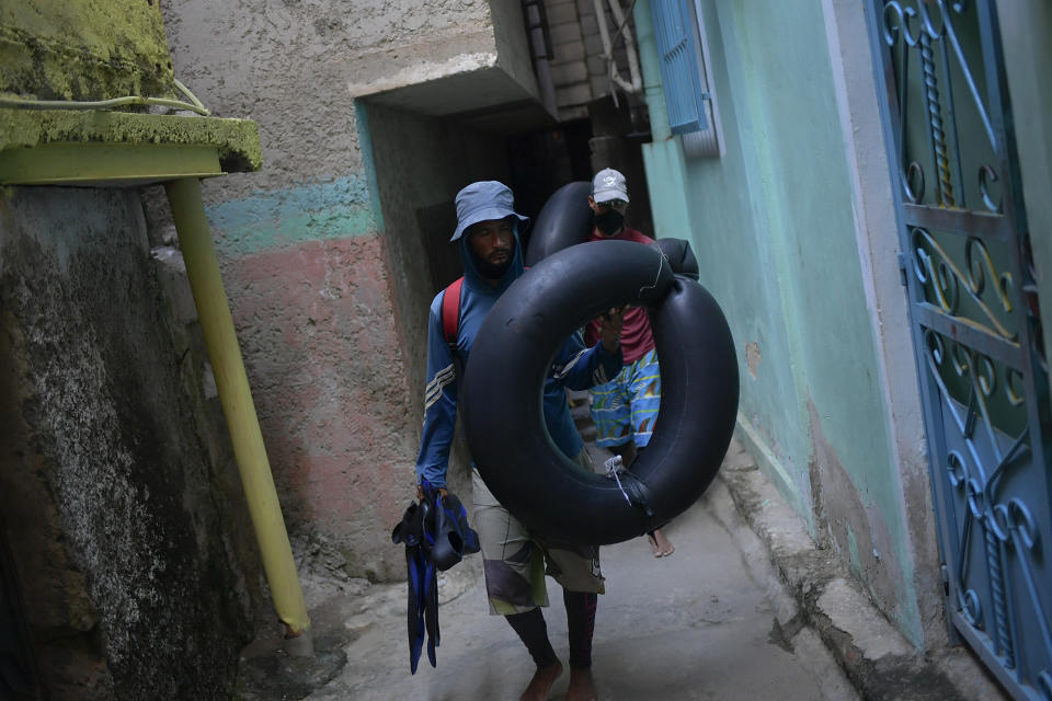 Jean Carlos Almeida, de 35 años, y Eric Méndez, de 40, regresan a casa después de pasar un día de pesca en mar abierto en sus cámaras neumáticas frente a Playa Escondida, en La Guaira, Venezuela, el viernes 14 de agosto de 2020, en medio de la pandemia de coronavirus. (Foto AP/Matias Delacroix)