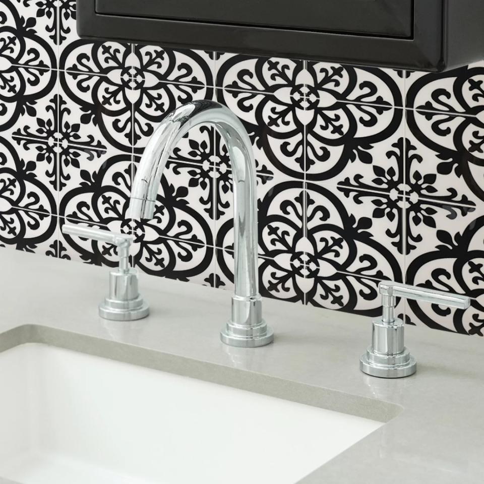 The peel-and-stick tiles with a black and white mosaic pattern behind a bathroom sink
