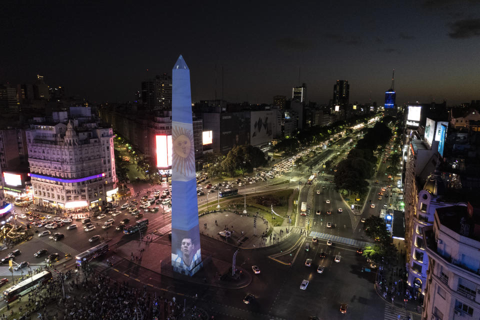 The Obelisk landmark is illuminated with a representation of the national flag, in Buenos Aires, Argentina, Saturday, Dec. 17, 2022, during a rally in support of the national soccer team a day ahead of the World Cup final against France. (AP Photo/Rodrigo Abd)