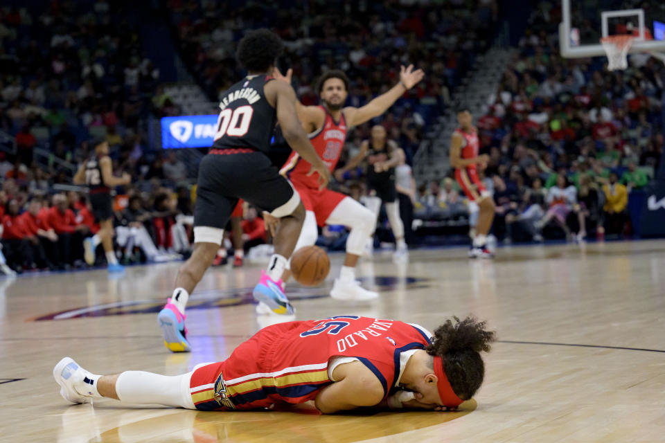 New Orleans Pelicans guard Jose Alvarado lies on the court after colliding with Portland Trail Blazers guard Scoot Henderson (00), resulting in a red bloody lip for Alvarado during the first half of an NBA basketball game in New Orleans, Saturday, March 16, 2024. (AP Photo/Matthew Hinton)