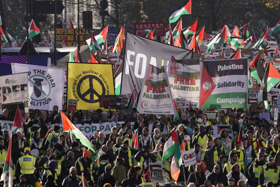 Protester hold flags and placards as they take part in a pro-Palestinian demonstration in London, Saturday, Nov. 25, 2023. (AP Photo/Alberto Pezzali)