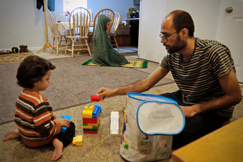 Khalid Omar plays with his son, Ferdous Omar, 2, at their home in New Bedford, while his wife, Khalida Hakimi, prays in the background. Each will take turns praying so that the other can take care of Ferdous. Afghanistan nationals Khalid Omar, his wife, Khalida Hakimi, and son, Ferdous Omar, have been living in New Bedford since February.