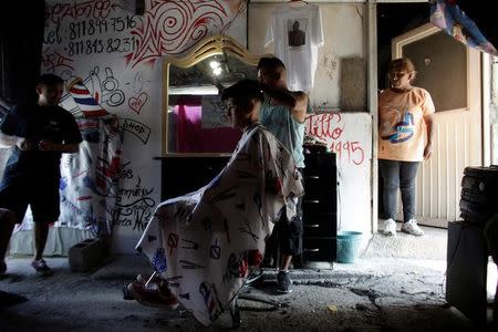 A barber gives a haircut to a young man, both attending the meetings of Raza Nueva in Christ, a project of the archdiocese of Monterrey, at a barbershop in the municipality of Juarez, on the outskirts of Monterrey, Mexico, June 25, 2016. REUTERS/Daniel Becerril