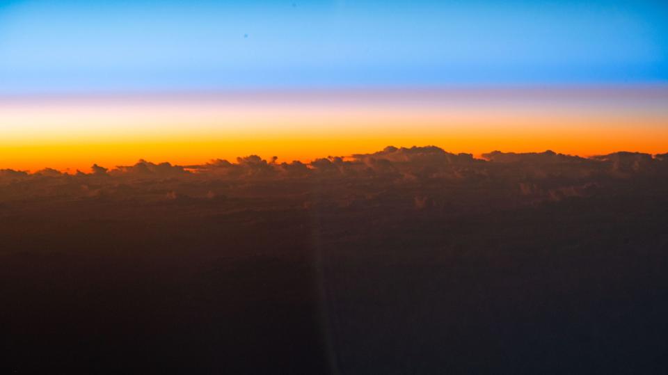 sunrise orange sky peeks above cloud tops