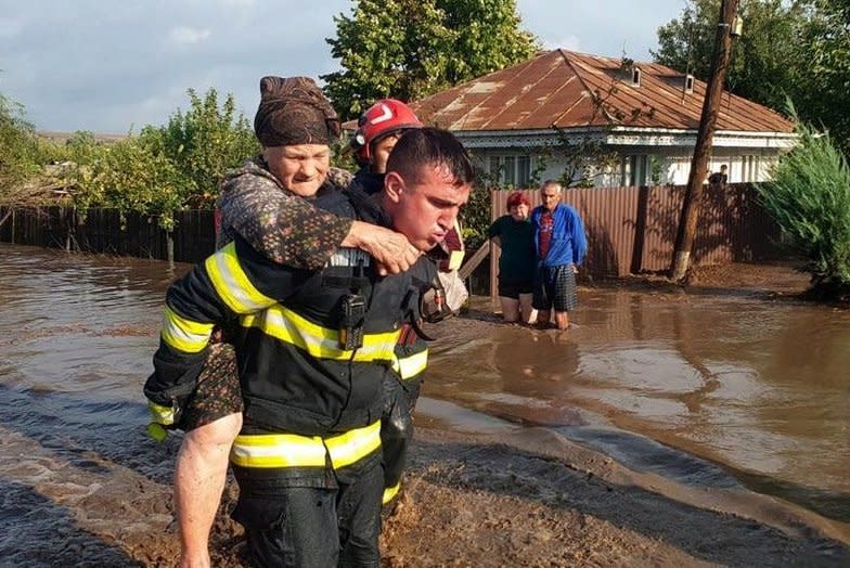 A first responder helps an elderly woman reach safety as heavy rainfalls inundate Romania and other parts of Europe with flooding that killed at least four in Romania. Photo by the Romanian General Inspectorate for Emergency Situations/EPA-EFE