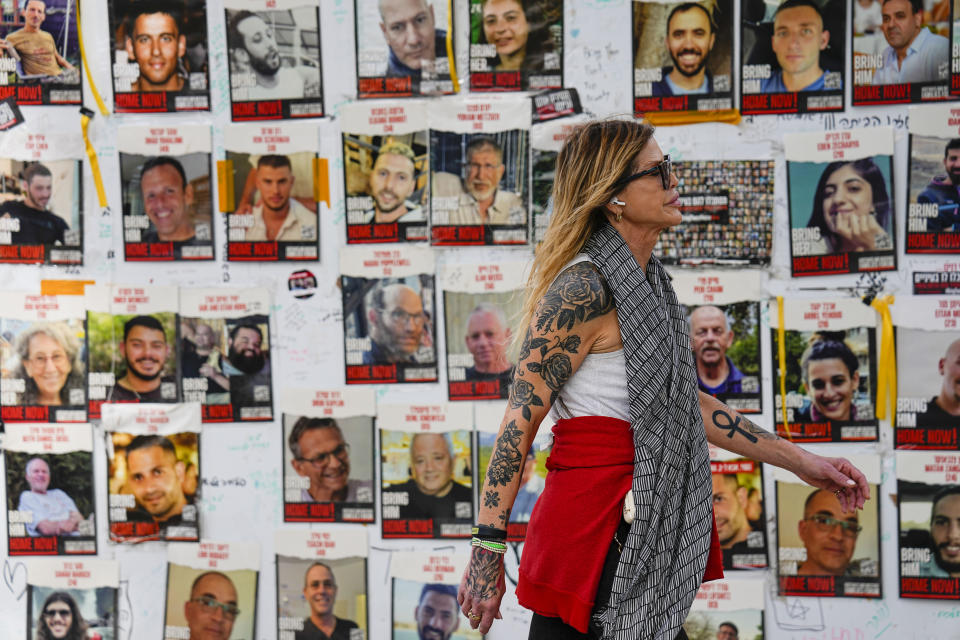 FILE - A woman walks past pictures of hostages in Tel Aviv, Israel, on Feb. 12, 2024. Fears are rising that time is running out for hostages in Gaza that are still alive. Nearly eight months later, there are 43 hostages whose remains are being held by Gaza militants and roughly 80 who have not been declared dead. (AP Photo/Ariel Schalit, File)