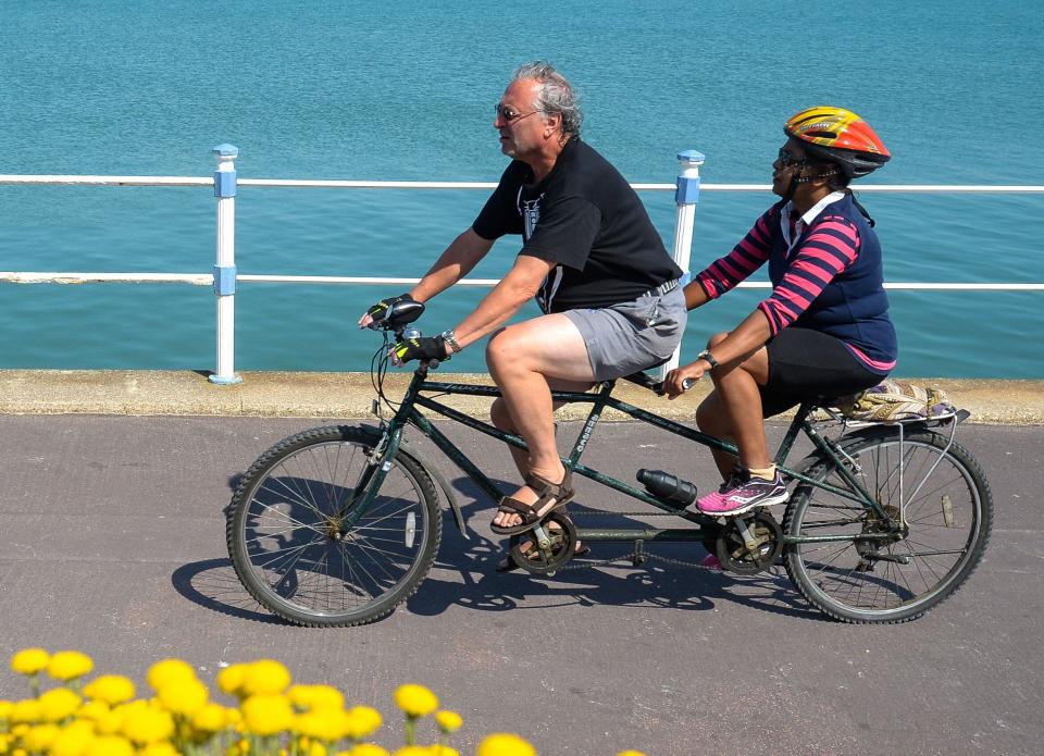 Tandem bike riders cycle along the seafront on June 24 in Weymouth, United Kingdom. Here, the tandem bike frame is clearly longer than the one depicted on the Dunkin' website. (Photo: Finnbarr Webster via Getty Images)