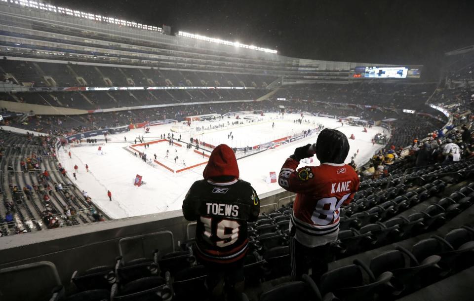 Two Chicago Blackhawks fans look out over the ice before an NHL Stadium Series hockey game between the Blackhawks and the Pittsburgh Penguins at Soldier Field on Saturday, March 1, 2014, in Chicago. (AP Photo/Charles Rex Arbogast)