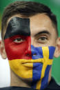 <p>A fan, with his face painted with the colors of the flags of Germany, left, and Sweden, waits for the start of the group F match between Germany and Sweden at the 2018. </p>