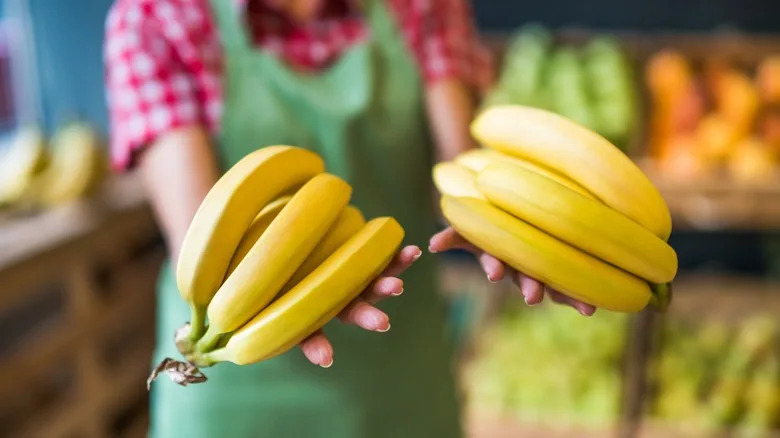 person green apron holding bananas