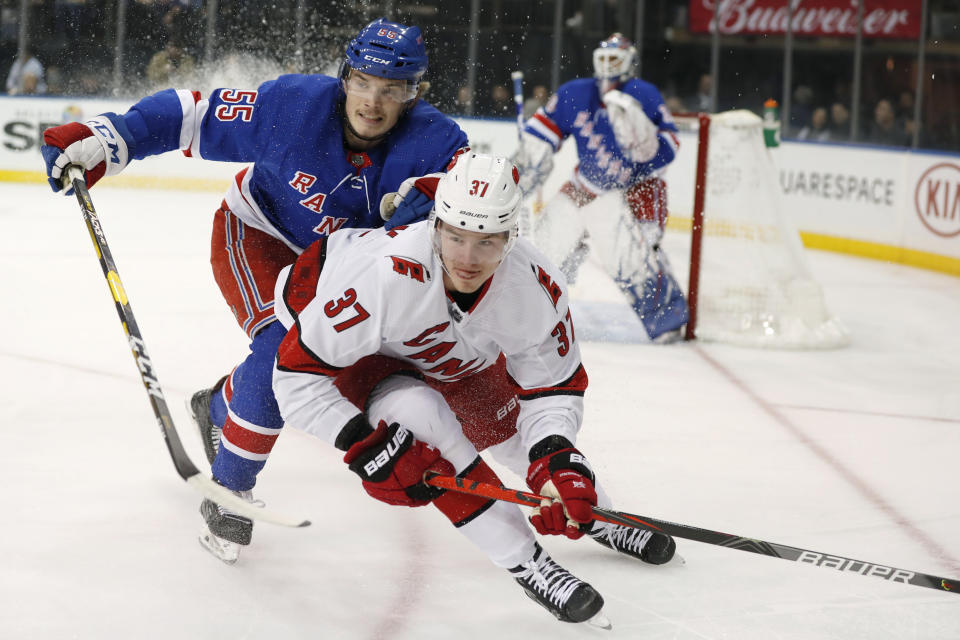 New York Rangers defenseman Ryan Lindgren (55) pressures Carolina Hurricanes right wing Andrei Svechnikov (37) as Svechnikov anticipates the puck deflecting off the boards toward the pair during the first period of an NHL hockey game Friday, Dec. 27, 2019, in New York. (AP Photo/Kathy Willens)