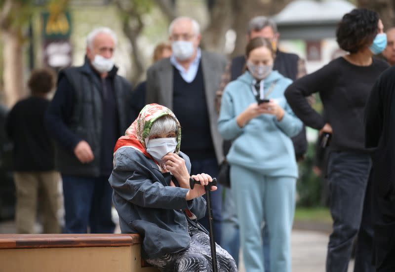 An elderly woman sits as she waits outside a polling station during a parliamentary election in Tbilisi