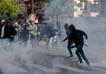 Hooded youths run through clouds of tear gas during clashes at a demonstration to protest the results of the first round of the presidential election in Paris, France, April 27, 2017. REUTERS/Gonzalo Fuentes
