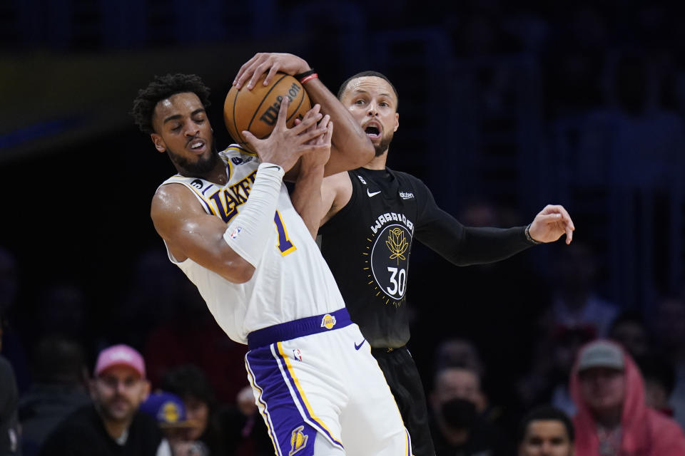 Los Angeles Lakers' Troy Brown Jr. (7) and Golden State Warriors' Stephen Curry (30) fight for a loose ball during the second half of an NBA basketball game Sunday, March 5, 2023, in Los Angeles. (AP Photo/Jae C. Hong)