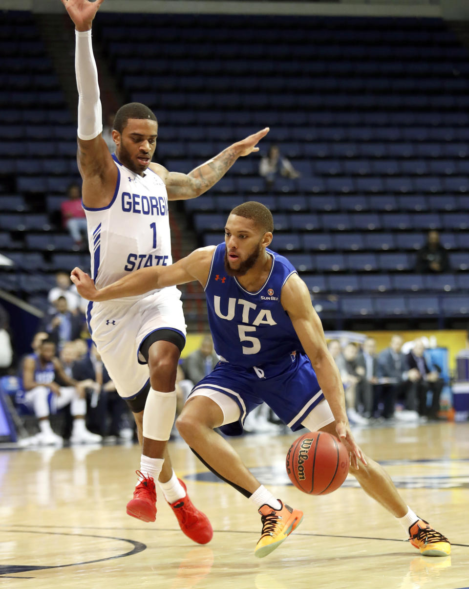 Texas-Arlington guard Edric Dennis (5) drives past Georgia State guard Damon Wilson (1) during the first half of the NCAA college basketball championship game of the Sun Belt Conference men's tournament in in New Orleans, Sunday, March 17, 2019. (AP Photo/Tyler Kaufman)