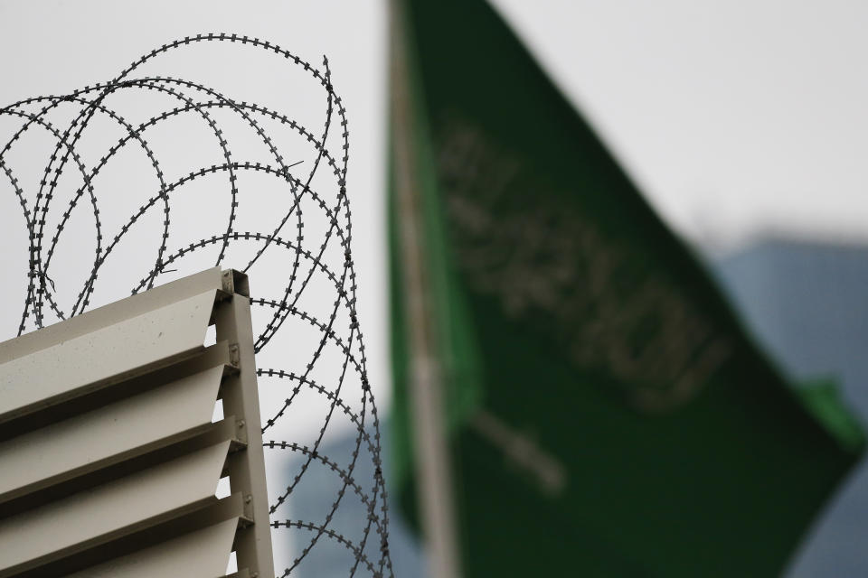 Behind barbed wire, Saudi Arabia's flag flies atop the country's consulate in Istanbul, Thursday, Oct. 18, 2018. Turkish crime-scene investigators finished an overnight search of both residence and a second search of the consulate itself amid Ankara's fears that Saudi writer Jamal Khashoggi was killed and dismembered inside the diplomatic mission in Istanbul. (AP Photo/Lefteris Pitarakis)