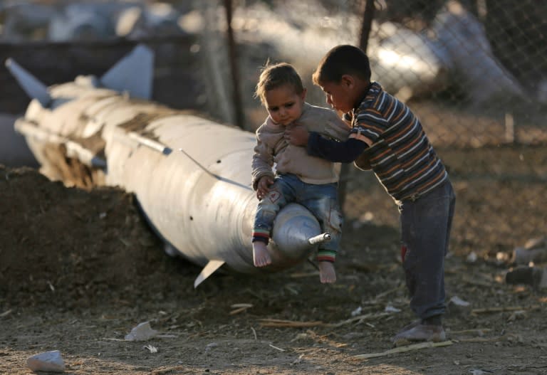A Syrian boy places another child on the tip of an abandoned missile at the Ash'ari camp for the displaced in rebel-held Eastern Ghouta outside Damascus on October 25, 2017