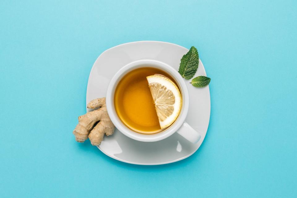 tea cup with lemon, ginger and mint on blue background