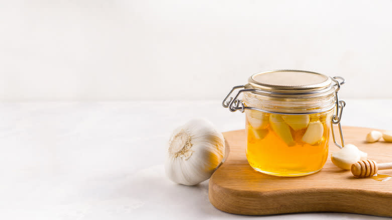 Glass jar of fermented garlic honey on wooden board