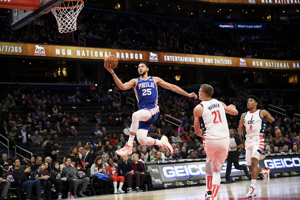 Philadelphia 76ers guard Ben Simmons (25) goes to the basket past Washington Wizards forward Moritz Wagner (21) and forward Rui Hachimura (8), of Japan, during the first half of an NBA basketball game, Thursday, Dec. 5, 2019, in Washington. (AP Photo/Nick Wass)