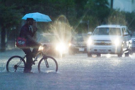 A man bikes through a heavily flooded road in downtown Houston, Texas May 30, 2015. REUTERS/Lee Celano