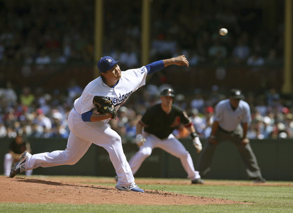 The Los Angeles Dodgers' starting pitcher Hyun-Jin Ryu, left, pitches with the Arizona Diamondbacks' Paul Goldschmidt, center, on first during the second game of their two-game Major League Baseball opening series at the Sydney Cricket Ground in Sydney, Sunday, March 23, 2014. (AP Photo/Rick Rycroft)