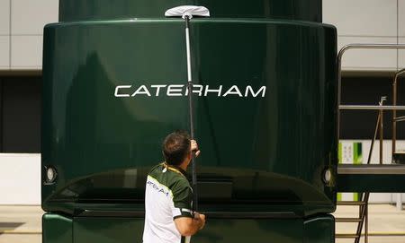 A member of the Caterham Formula One team cleans one of the team vehicles ahead of the British Grand Prix at the Silverstone race circuit, central England, July 3, 2014. REUTERS/Phil Noble