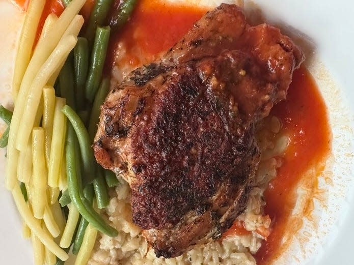 A blue and white Amtrak plate with pan-roasted chicken, rice, and green and yellow string beans.