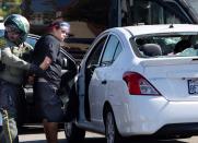 An unidentified woman is taken into custody after witnesses said she drove her car into a crowd of protesters in Yorba Linda, Calif., Saturday, Sept. 26, 2020. Authorities said people were struck by a car and injured during a Black Lives Matter protest and counter protest about 30 miles southeast of Los Angeles. Orange County Sheriff's Department spokeswoman Carrie Braun says the injured were transported to a hospital with non-life-threatening injuries and the driver was detained. (Mindy Schauer/The Orange County Register via AP)