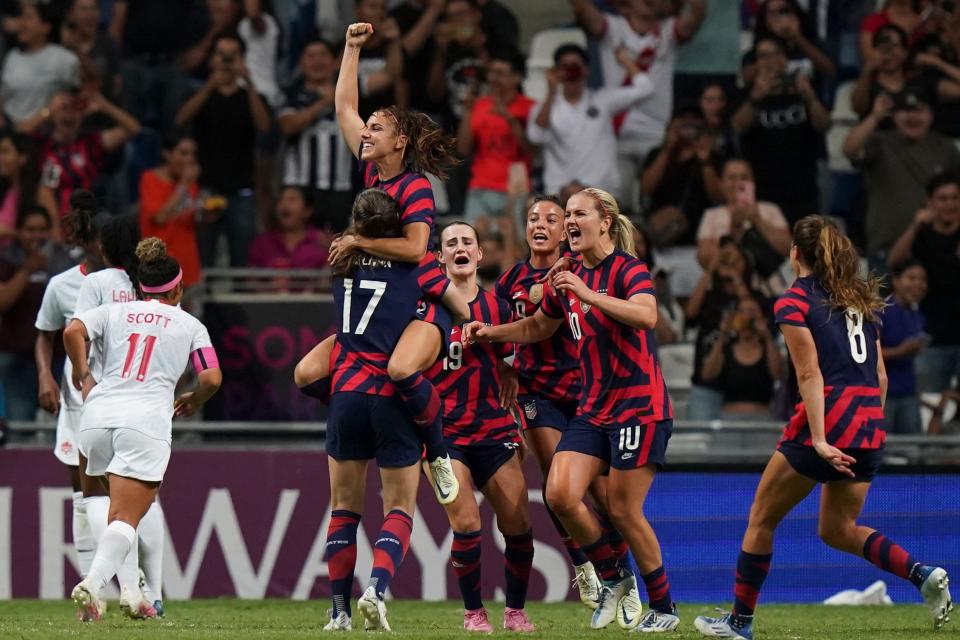 Alex Morgan celebrates with teammates after converting a penalty kick against Canada.