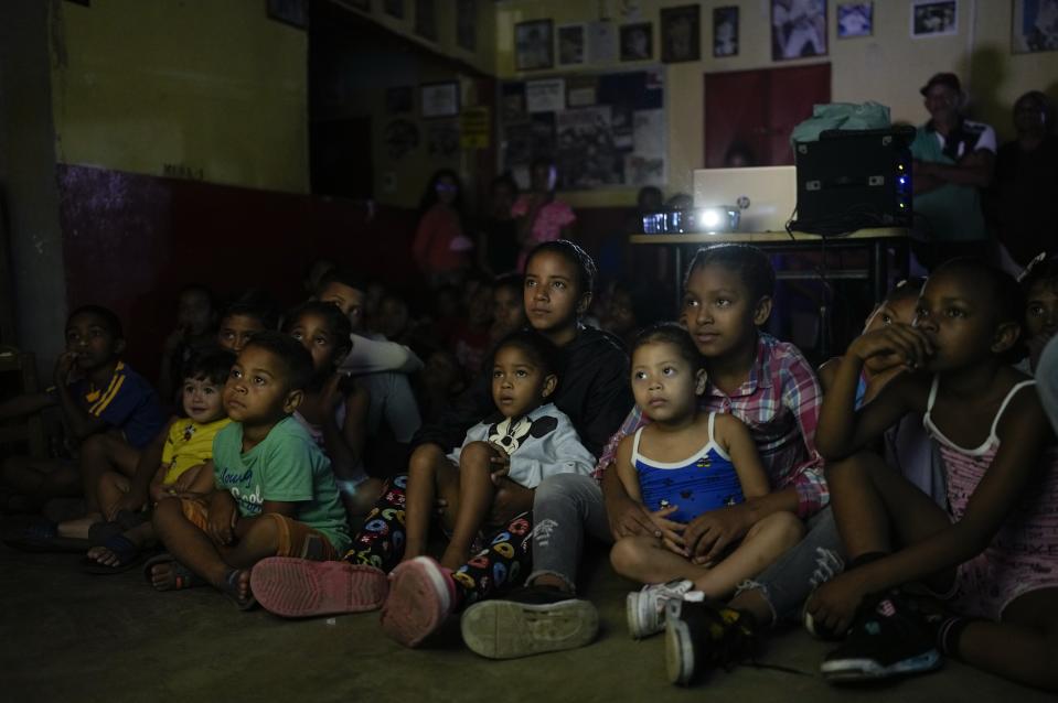 Varios niños miran la película animada "Un gato en París" durante un festival de cine en el barrio de San Agustín de Caracas, Venezuela, el 25 de mayo de 2022. (AP Foto/Ariana Cubillos)