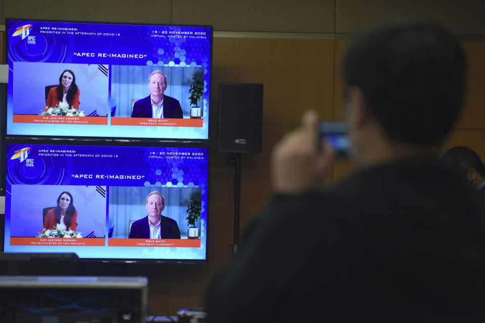 In this photo released by Malaysia Department of Information, screens show New Zealand's Prime Minister Jacinda Ardern, left, and Microsoft President Brad Smith speak via virtual meeting during the APEC CEO Dialogues 2020, ahead of the Asia-Pacific Economic Cooperation (APEC) leaders' summit in Kuala Lumpur, Malaysia, Friday, Nov. 20, 2020. (Fandy Azlan/Malaysia Department of Information via AP)