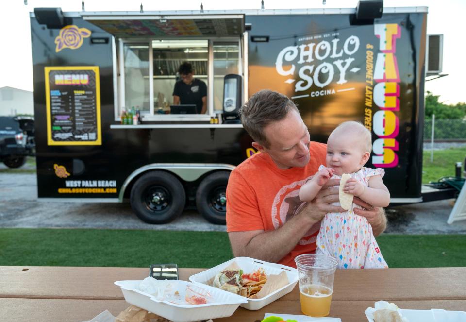 Trey Smith has dinner with his baby daughter, Alice, in front of the mobile Cholo Soy Cocina food truck outside of Civil Society Brewing in West Palm Beach.