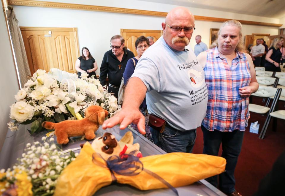 Jeffrey Meredith reaches out to touch a stuffed animal atop the casket for an unidentified boy during a memorial service at Weathers Funeral home Wednesday in Salem, Indiana. The boy's body was found in a suitcase in April.